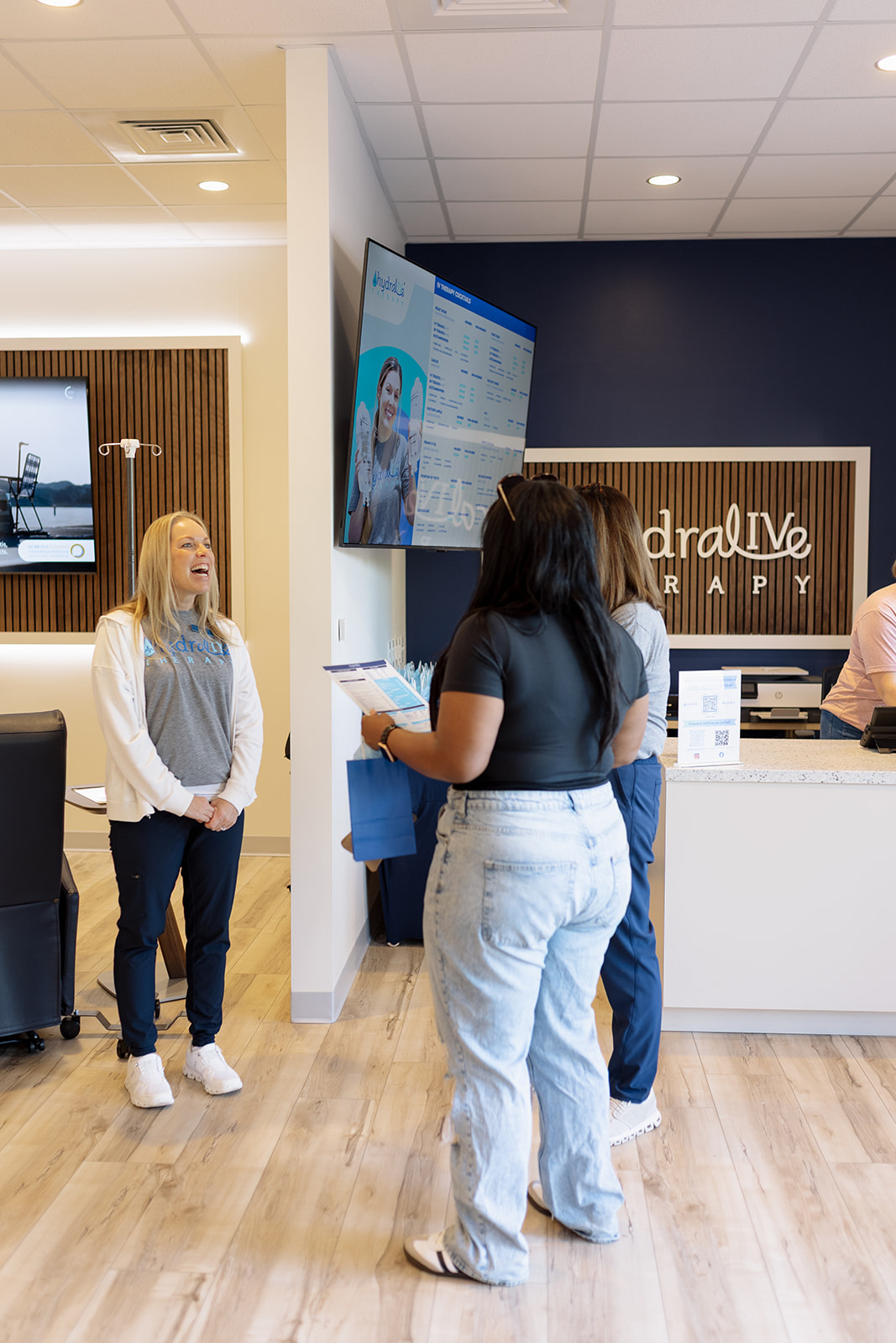 The glowing Hydralive Therapy sign over the navy brand wall inside the Huntersville IV lounge