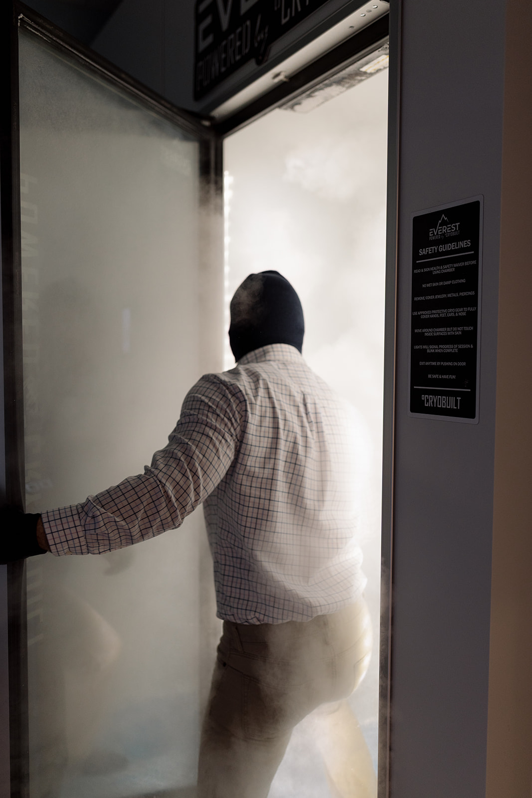 A client stepping into the whole-body cryotherapy chamber at Hydralive Huntersville as cold vapor rolls out