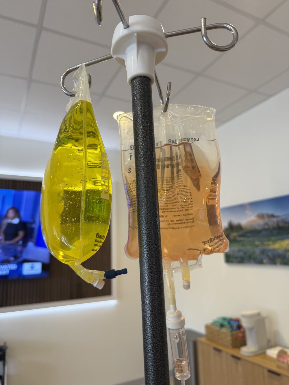 A mixed vitamin drip bag beside a saline bag on the IV pole