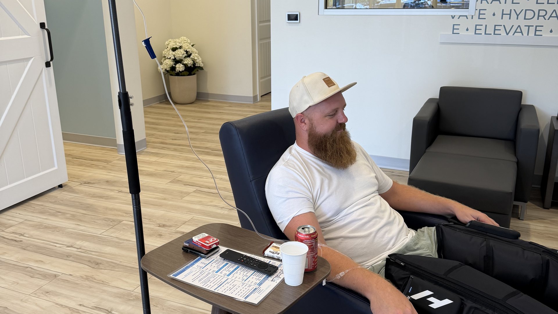A client settled into a recliner with an IV line running in the Hydralive Huntersville lounge
