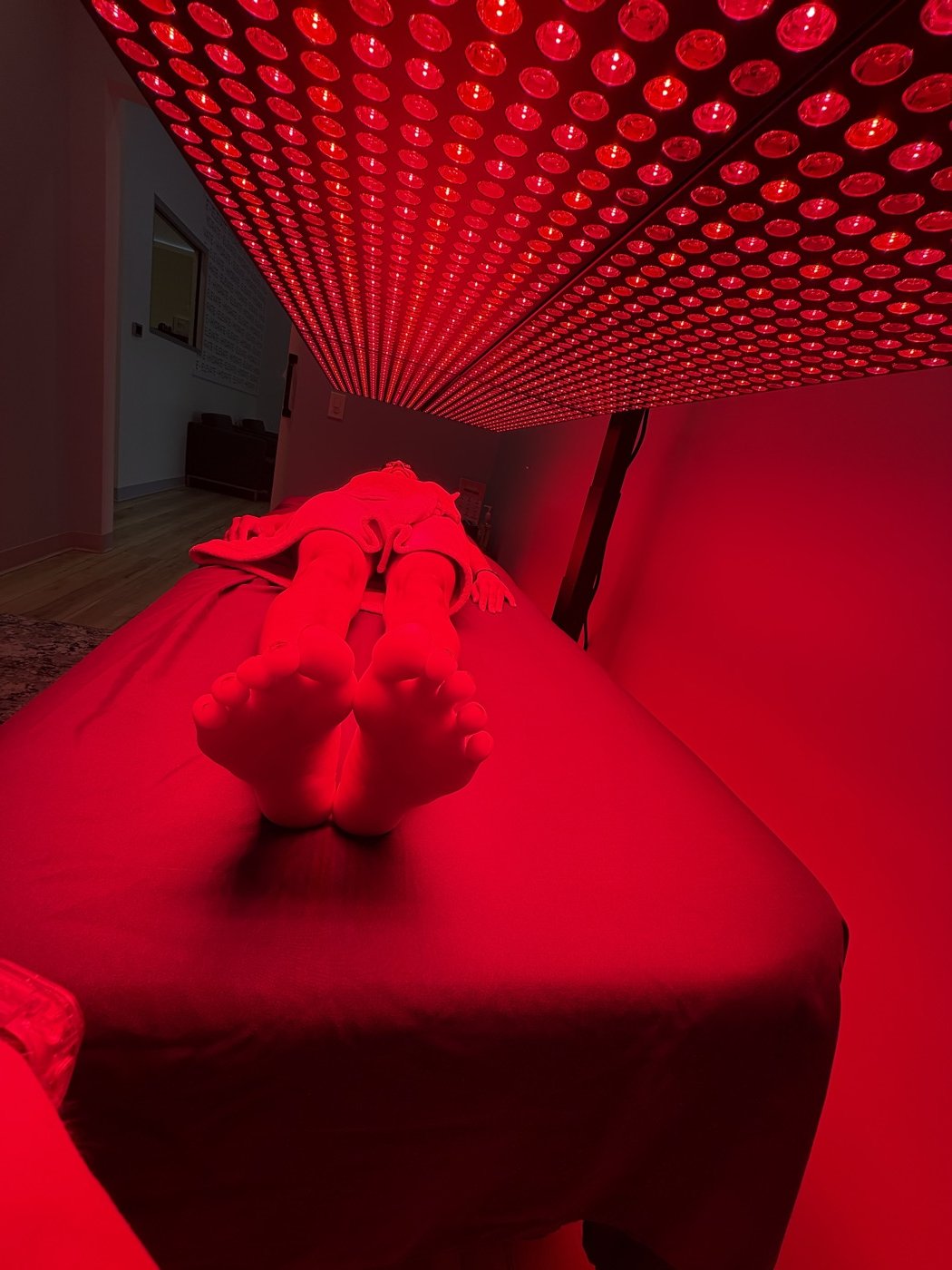 A client's legs and feet bathed in red light under the panel array