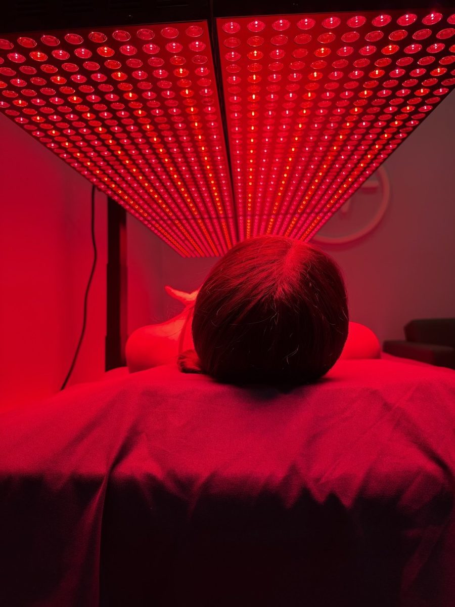 The lit red light panel array glowing above the treatment table